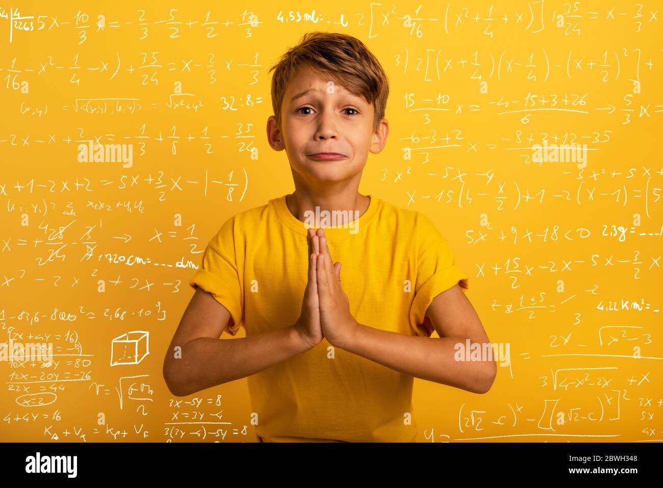 Child is pleading because he does not want to study. Yellow background Stock Photo