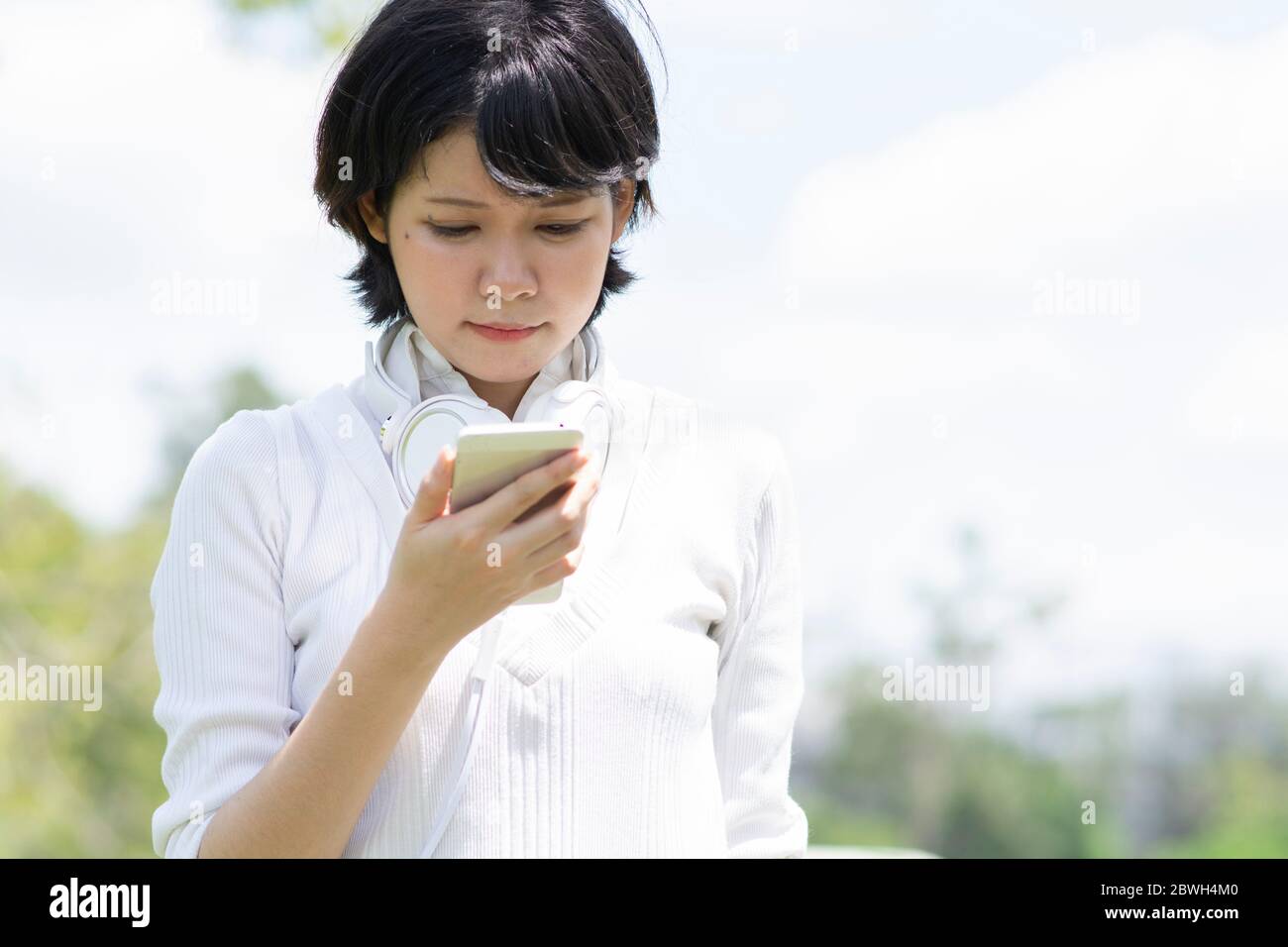 Stressed asian woman looking at mobile phone. Blur building background. Stock Photo