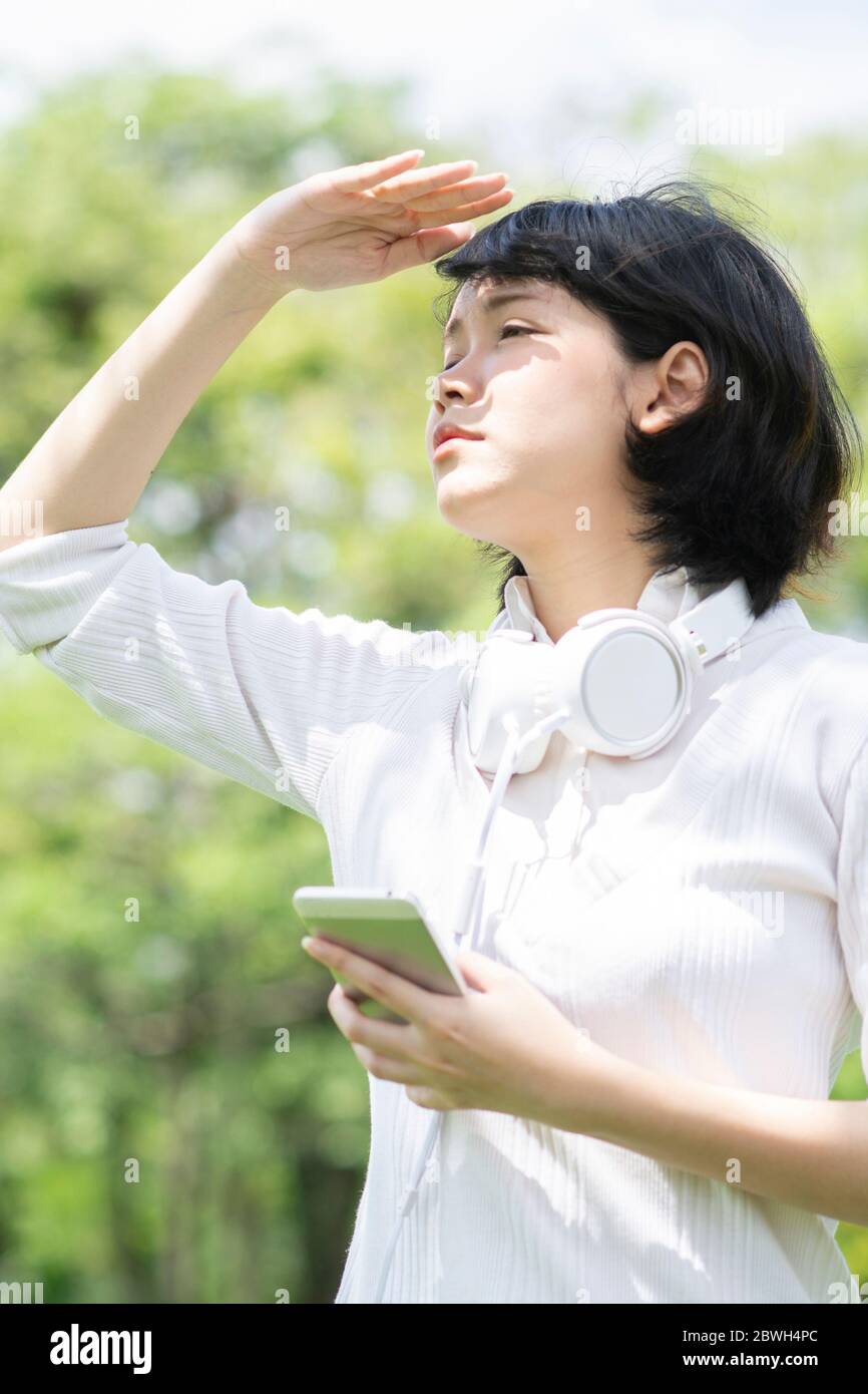 Stressed asian woman looking for something with mobile phone in her hand. Blur building background. Stock Photo