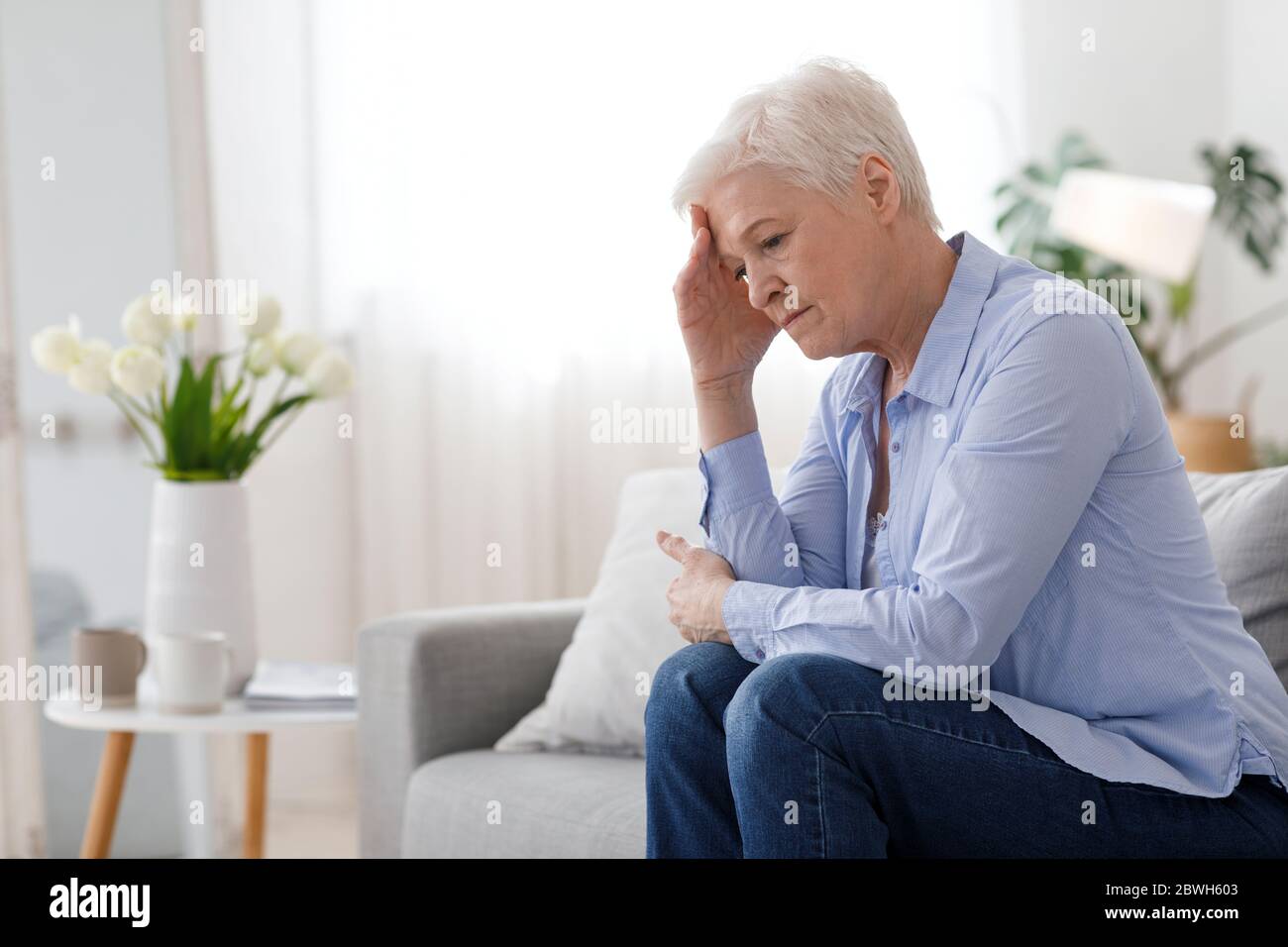 Woman Climax. Portrait Of Depressed Elderly Woman Sitting On Couch At Home Stock Photo