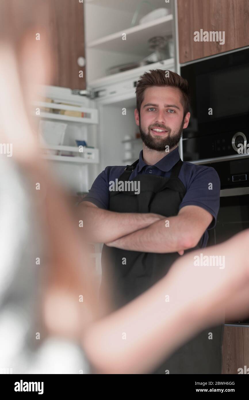 Smiling attractive young man standing near refrigerator Stock Photo