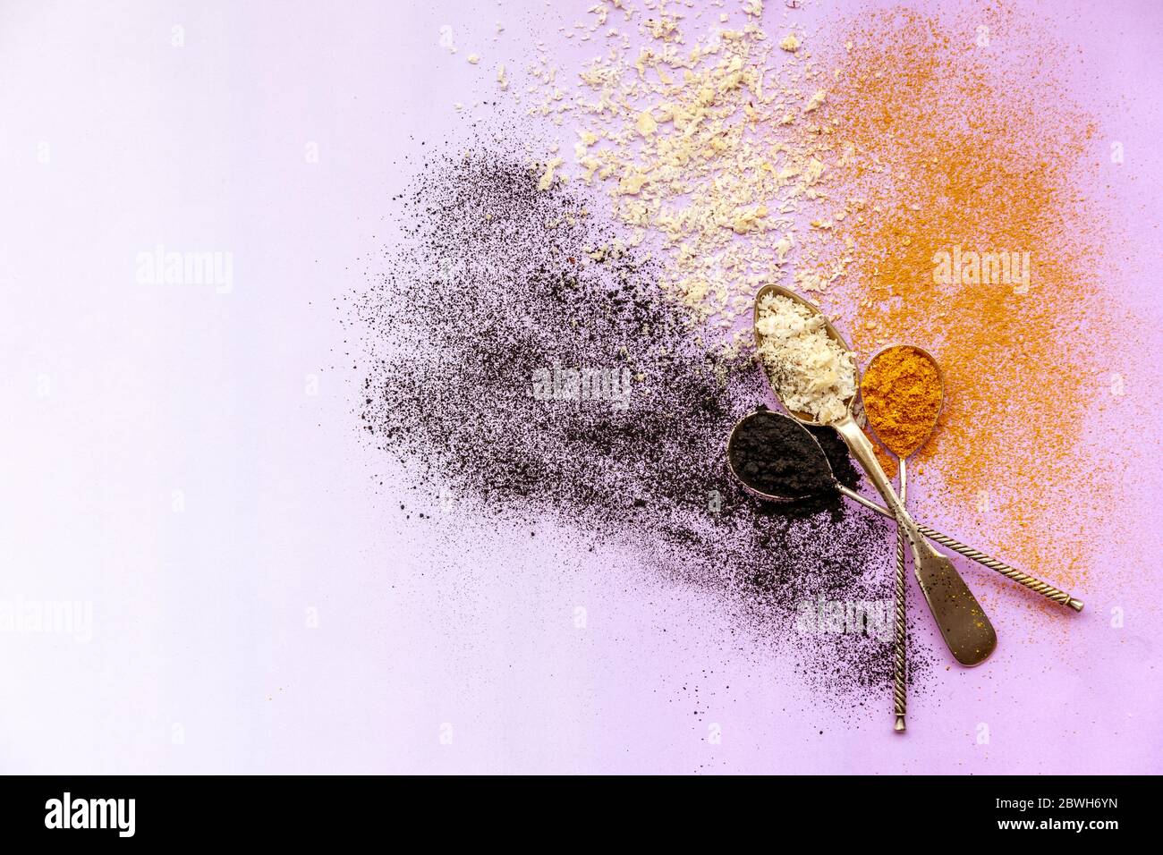 Color explosion of black white and orange - activated carbon, coconut and turmeric from three silver spoons Stock Photo