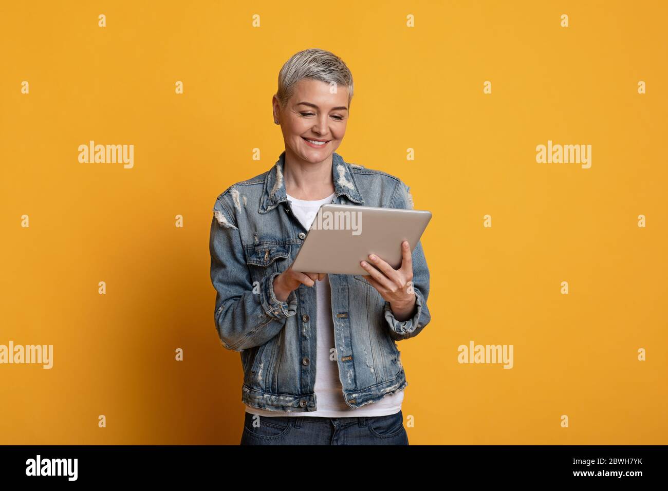 Great App. Beautiful middle-aged woman in stylish clothes using digital tablet Stock Photo