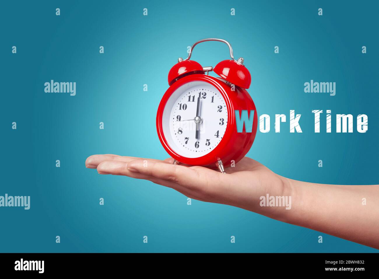 red clock with alarm on hand over blue background, work time concept