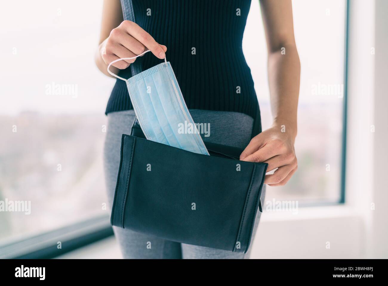 COVID-19 Prevention woman bringing medical mask in her purse for walking outside doing errands in public spaces and store. Coronavirus face masks protection obligatory wear to work. Stock Photo