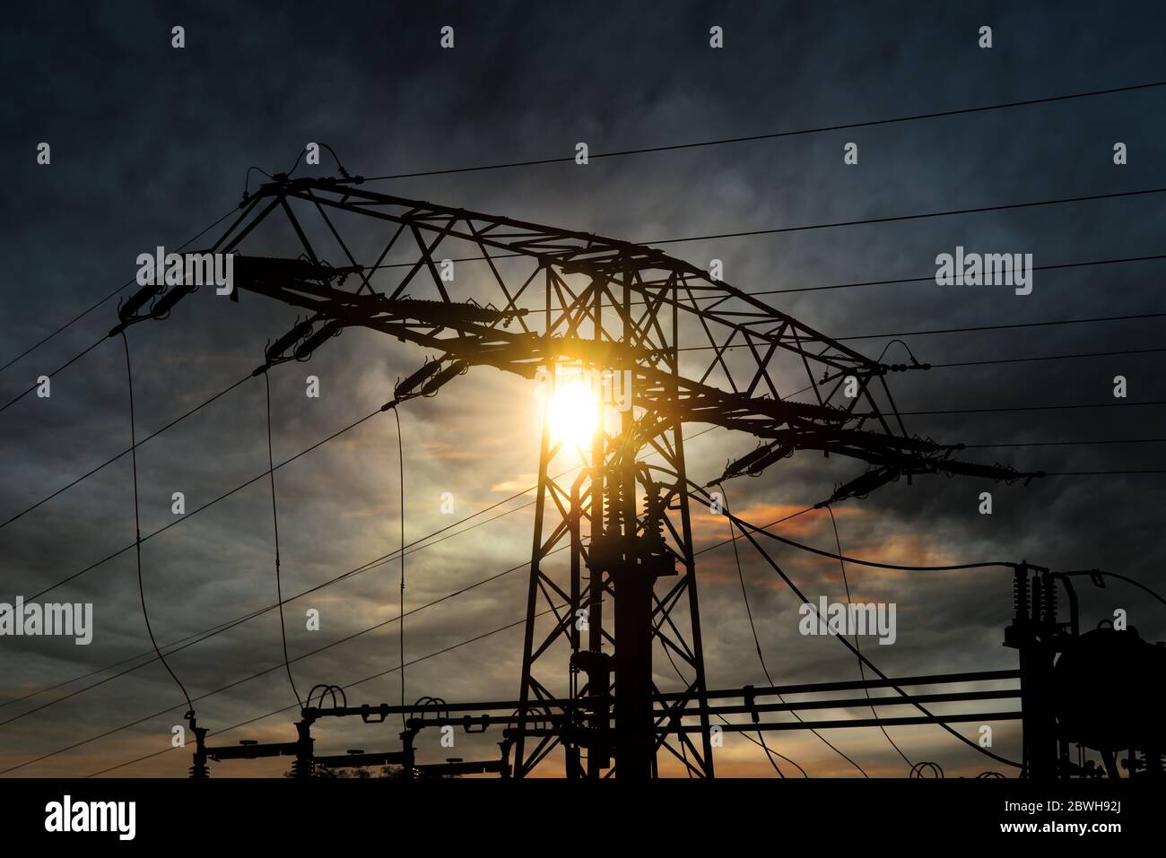Power transmission tower with sun and back lit. Sun shines through a high voltage pylon Stock Photo