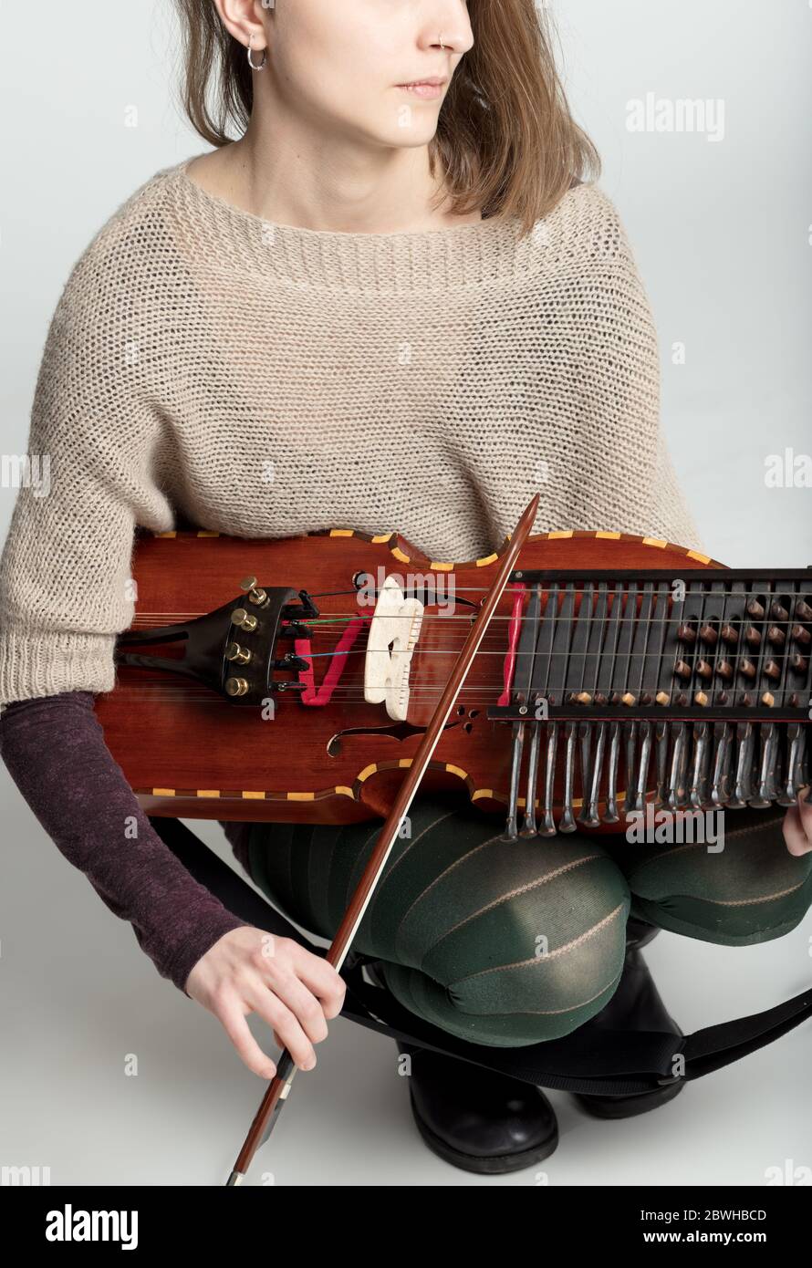 Young woman playing a traditional nyckelharpa in a close up on the bow