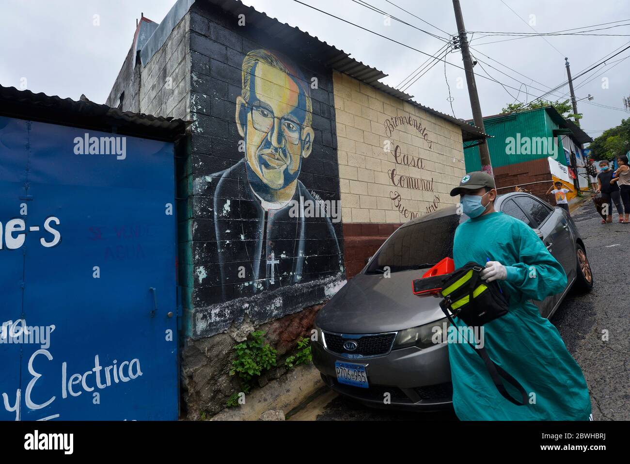 Mejicanos, El Salvador. 1st June, 2020. A first responder wearing PPE walks by a mural depicting Saint Oscar Romero.Tropical Storm Amanda reached El Salvador on Friday May 29th and has left 16 deaths so far as reported by the authorities. Credit: Camilo Freedman/ZUMA Wire/Alamy Live News Stock Photo