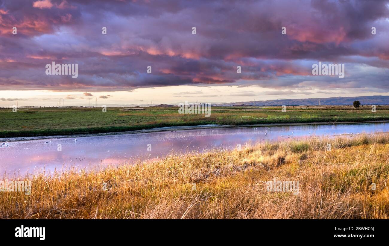 Dramatic sunset landscape with storm clouds reflected in the restored wetlands of South San Francisco Bay Area; Mountain View, California Stock Photo