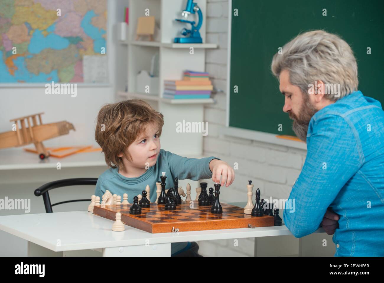 Chess success and winning. Family relationship with son. Cute boy developing chess strategy. Concept of education and teaching. Educational games. Stock Photo