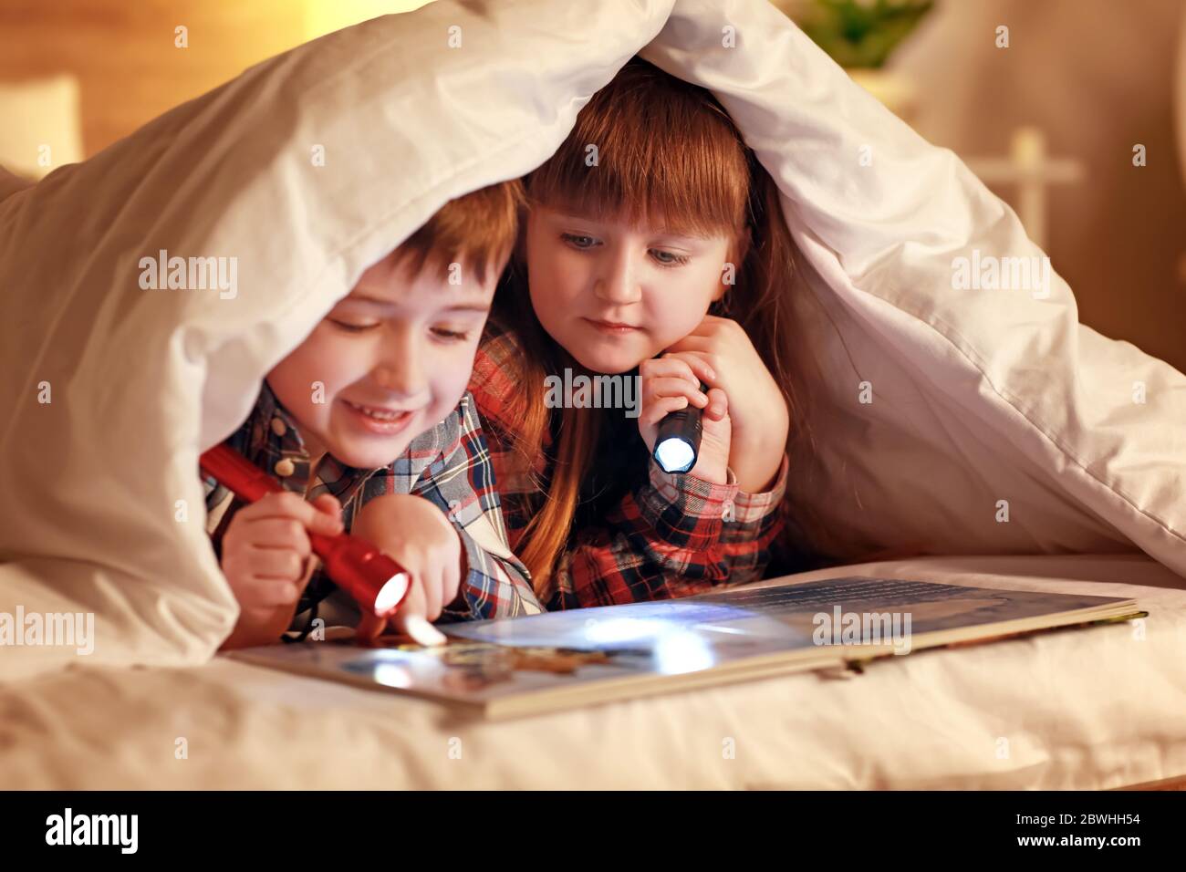 Little children reading book under blanket at night Stock Photo Alamy