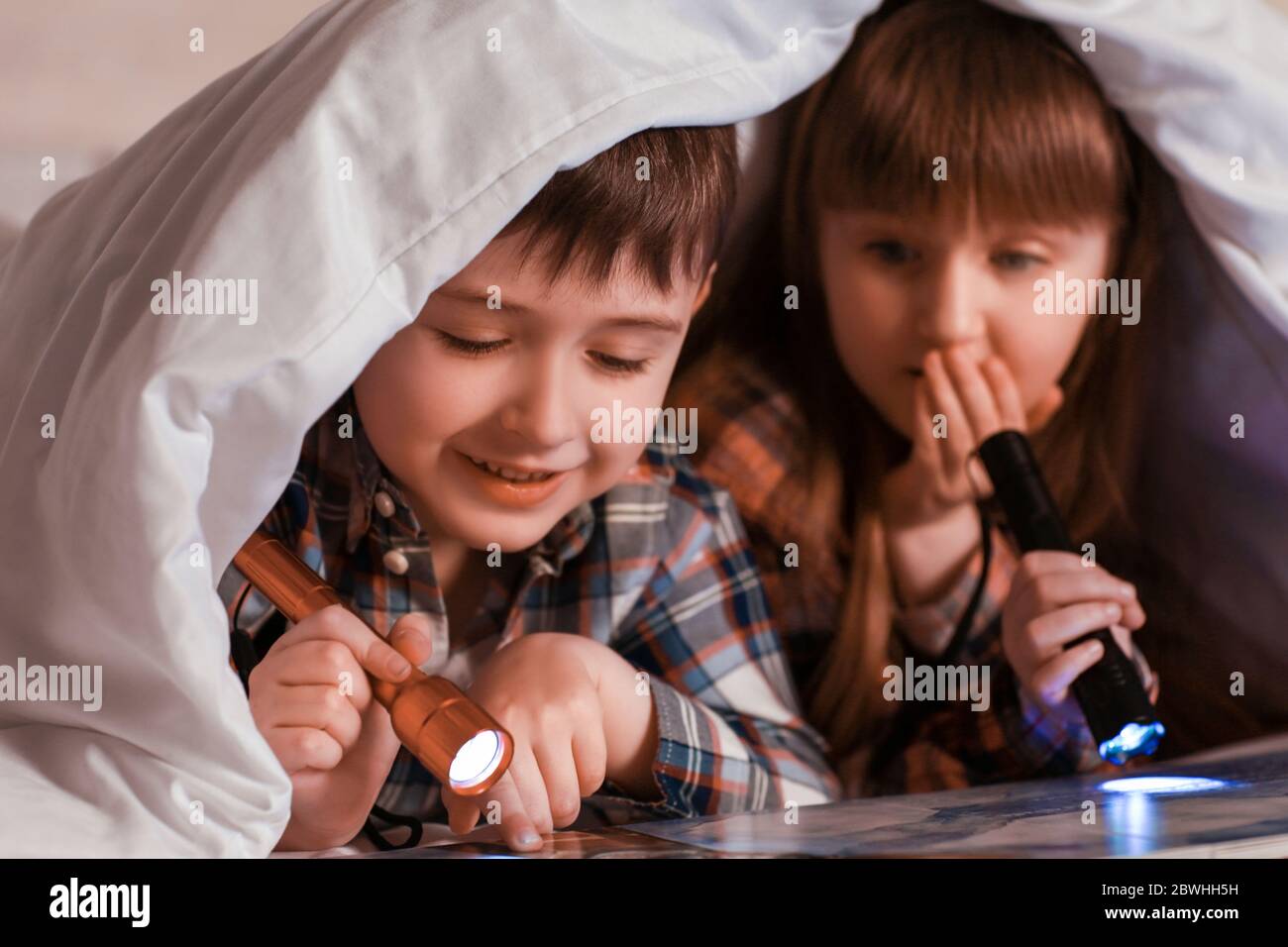 Little children reading book under blanket at night Stock Photo Alamy