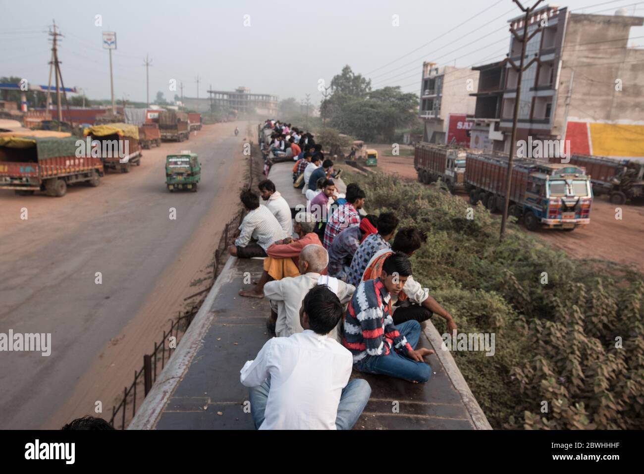 Men on top of overcrowded train passes through a small town in Madhya Pradesh, India. Indian Railways. Stock Photo