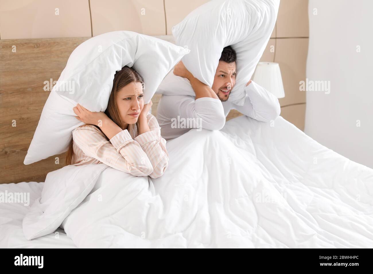 Young couple cannot sleep because of rowdy neighbours Stock Photo