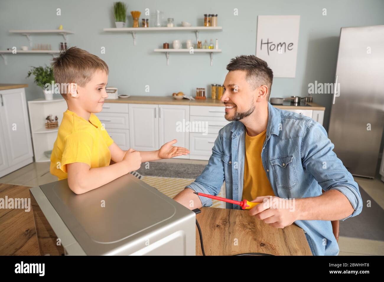Little son helping his father to repair microwave oven in kitchen Stock ...