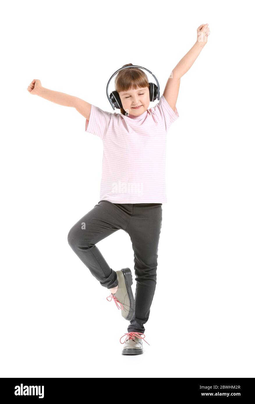Cute little girl dancing and listening to music against white