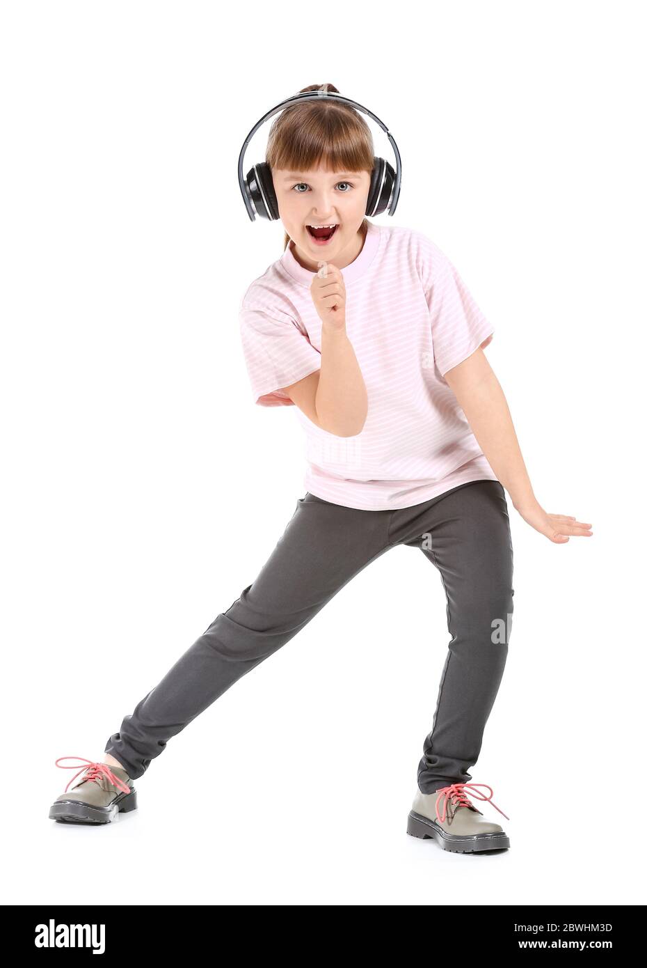 Cute little girl dancing and listening to music against white