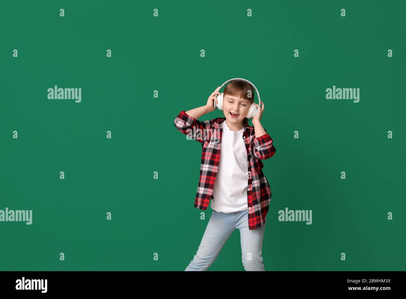 Cute little girl dancing and listening to music against color