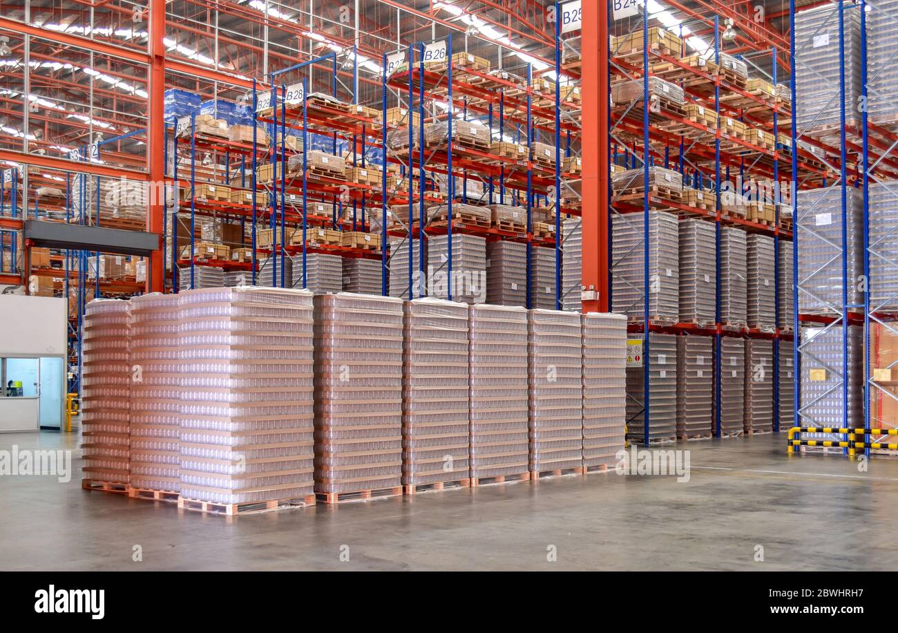 Pallets of empty plastic glass stack in shorting area inside distribution warehouse. Stock Photo
