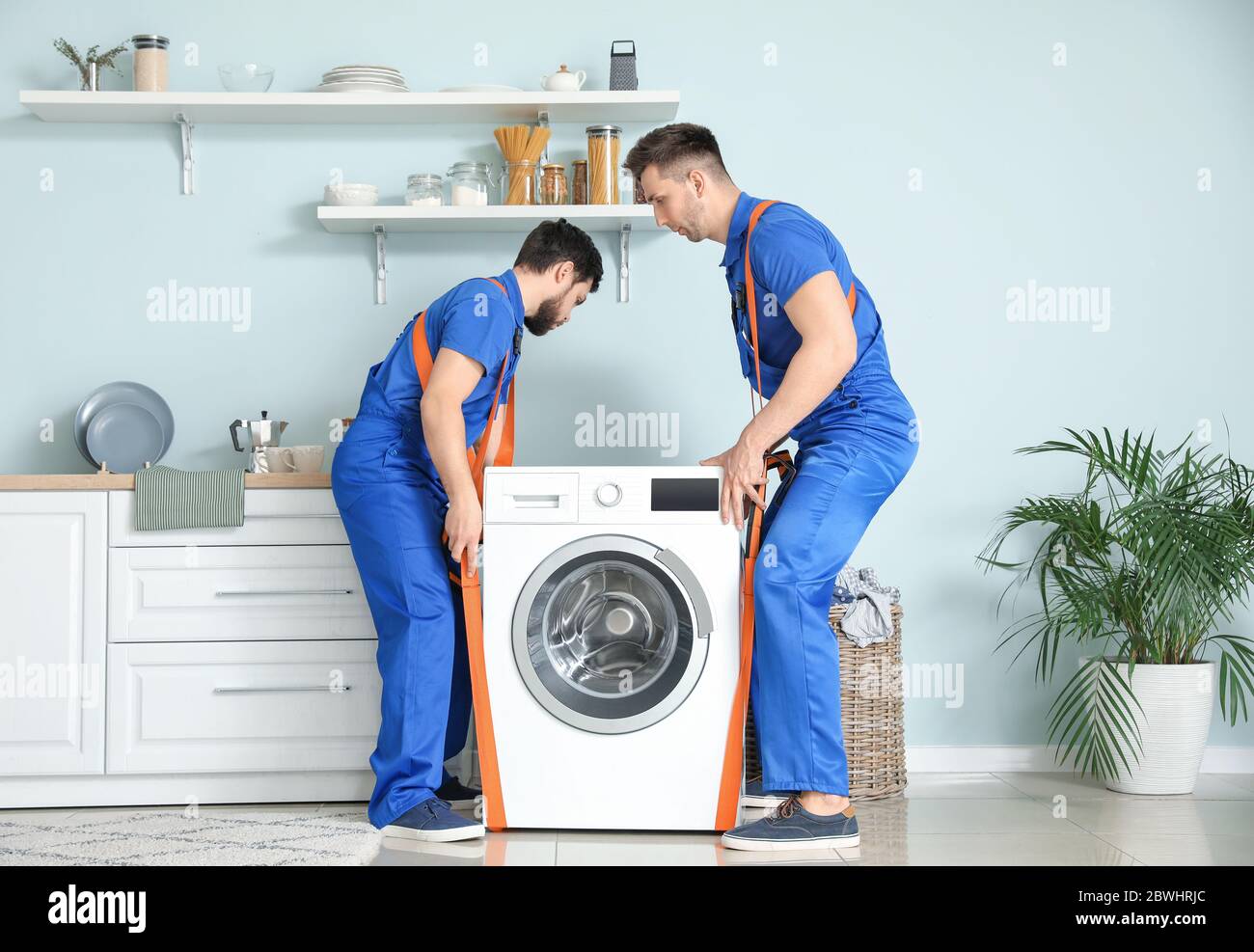 Loaders carrying washing machine by using cargo belts Stock Photo Alamy