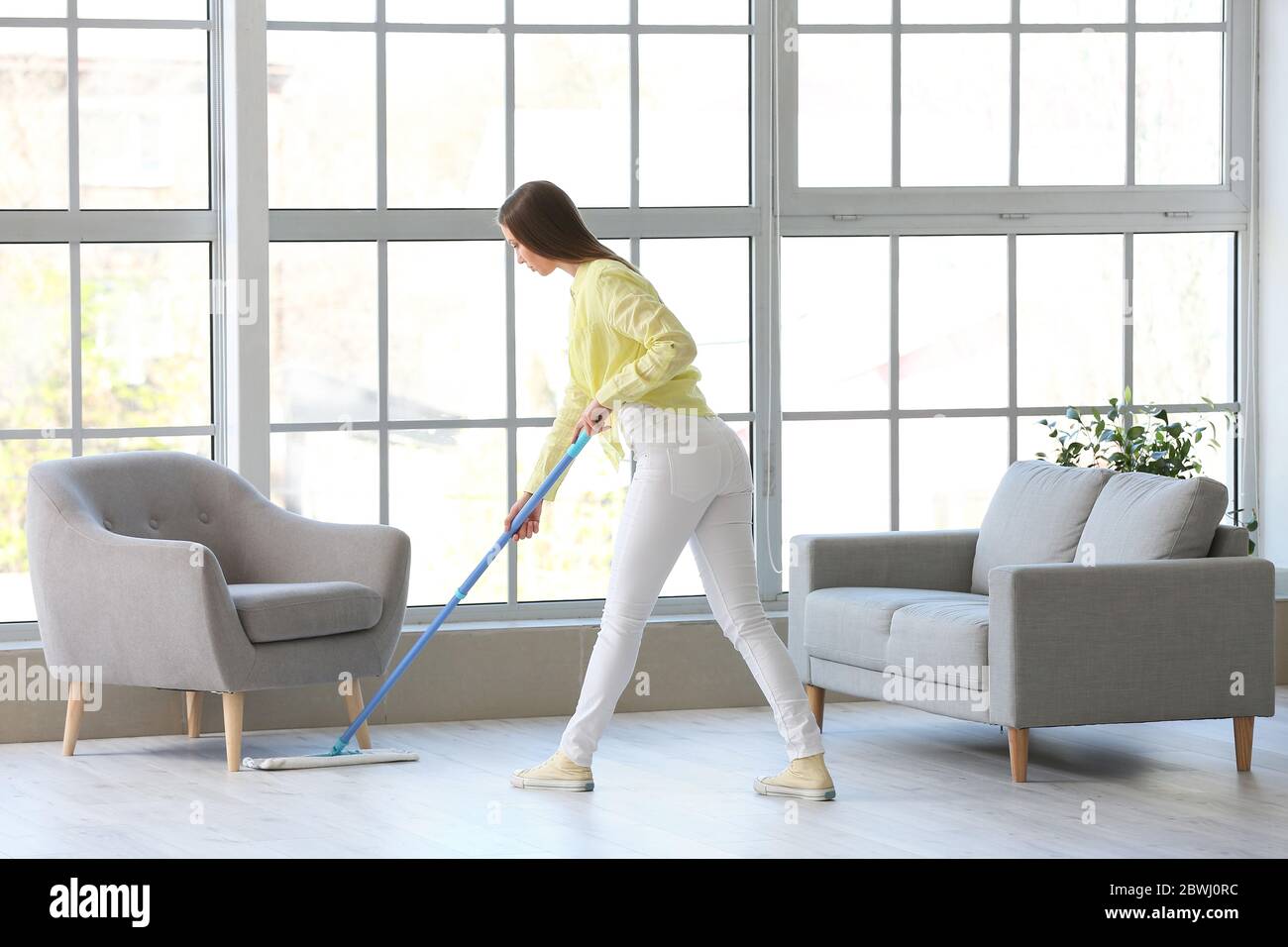 Young woman mopping floor in room Stock Photo