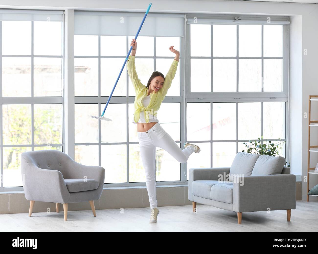 Young woman having fun while mopping floor in room Stock Photo
