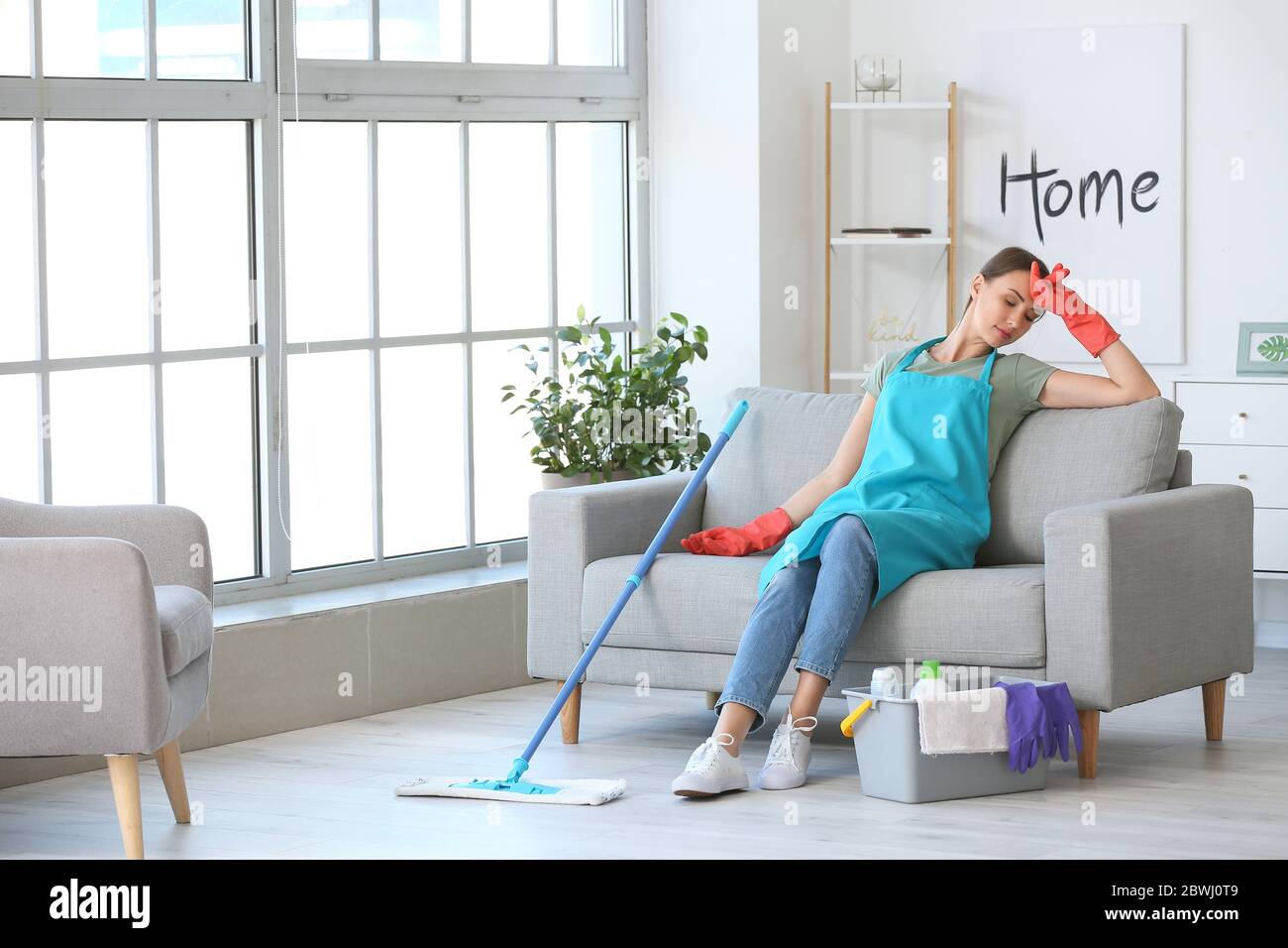 Tired young woman after mopping floor in room Stock Photo