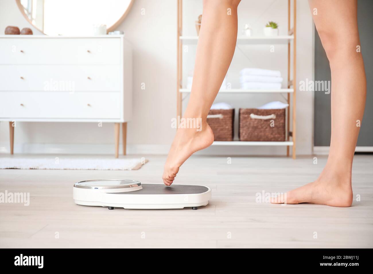 Young woman measuring her weight at home Stock Photo - Alamy