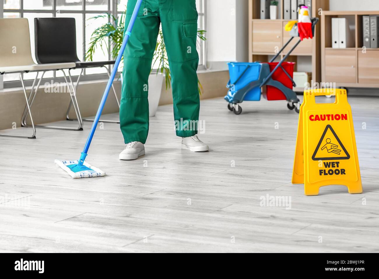 Male janitor mopping floor in office Stock Photo
