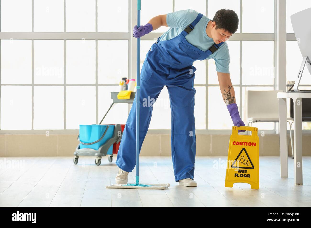 Male janitor mopping floor in office Stock Photo