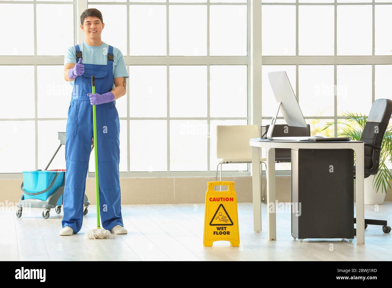 Male janitor mopping floor in office Stock Photo