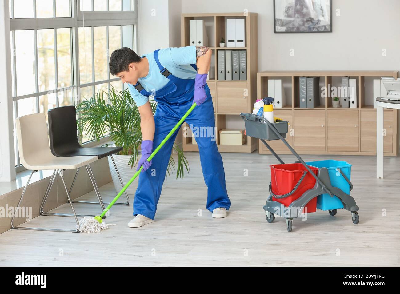 Male janitor mopping floor in office Stock Photo