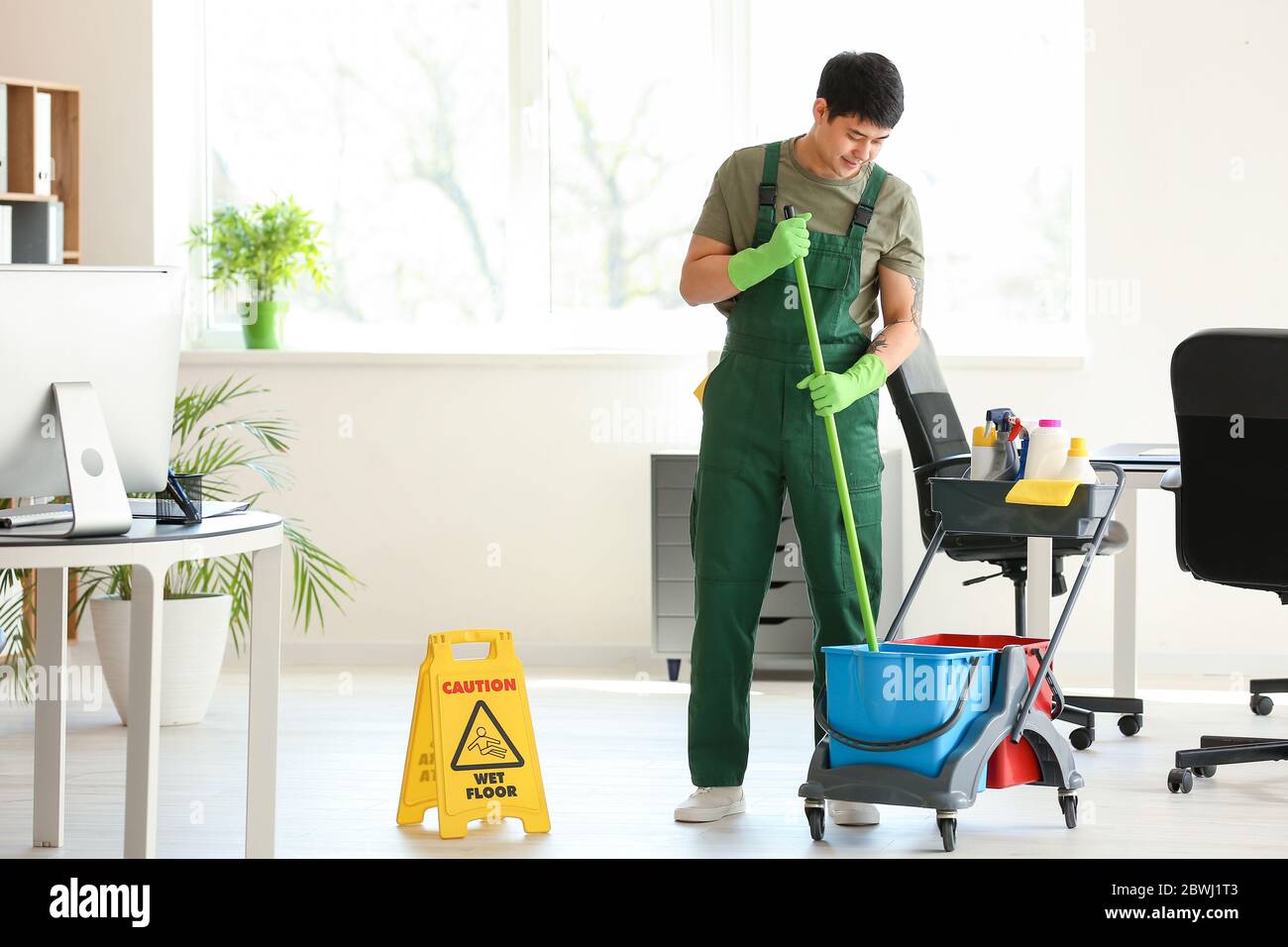 Male janitor mopping floor in office Stock Photo