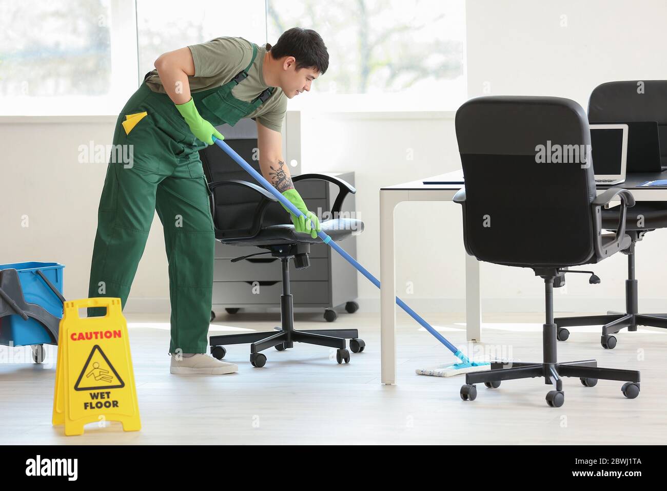 Male janitor mopping floor in office Stock Photo