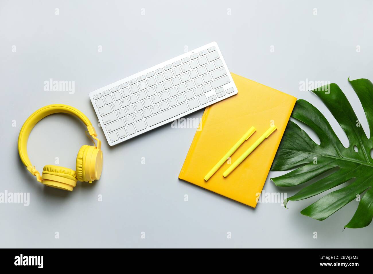 Computer keyboard with notebook, headphones and pens on light background Stock Photo