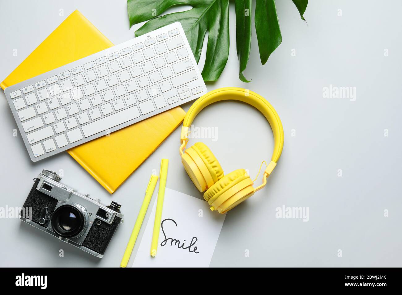 Computer keyboard with notebook, headphones and photo camera on light background Stock Photo