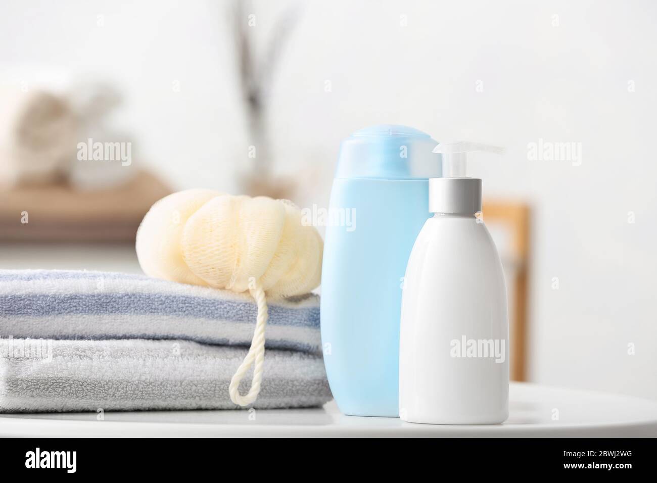 Different shower gels, towel and loofah on table in bathroom Stock