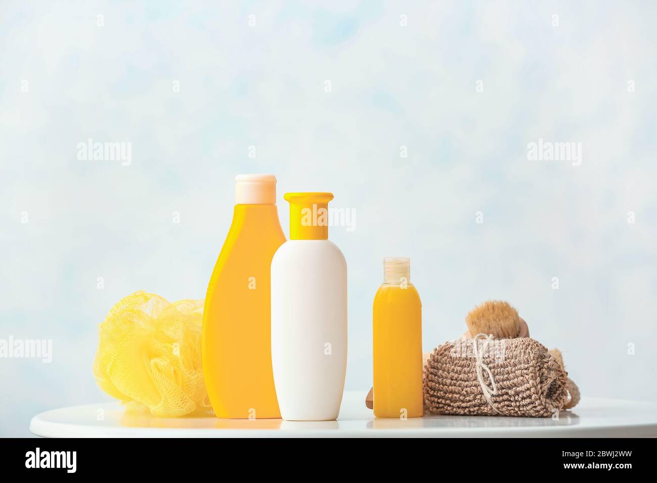 Different shower gels, towel and loofah on table in bathroom Stock