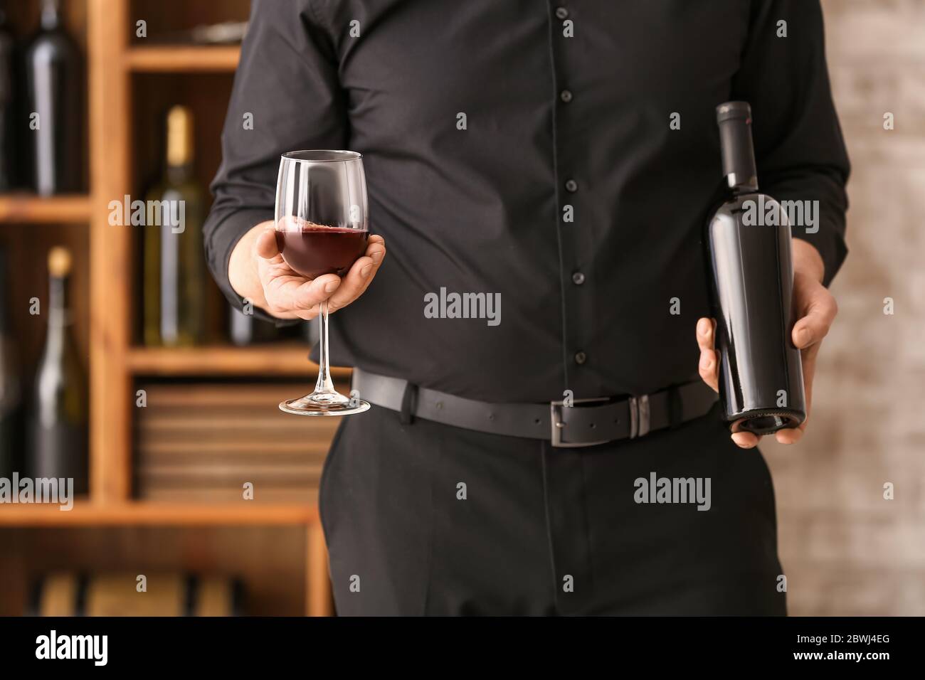 Man with bottle and glass of tasty wine in cellar Stock Photo - Alamy