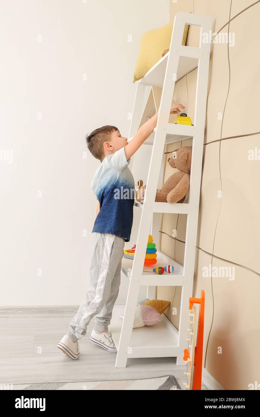 Little boy near rack with toys at home Stock Photo - Alamy