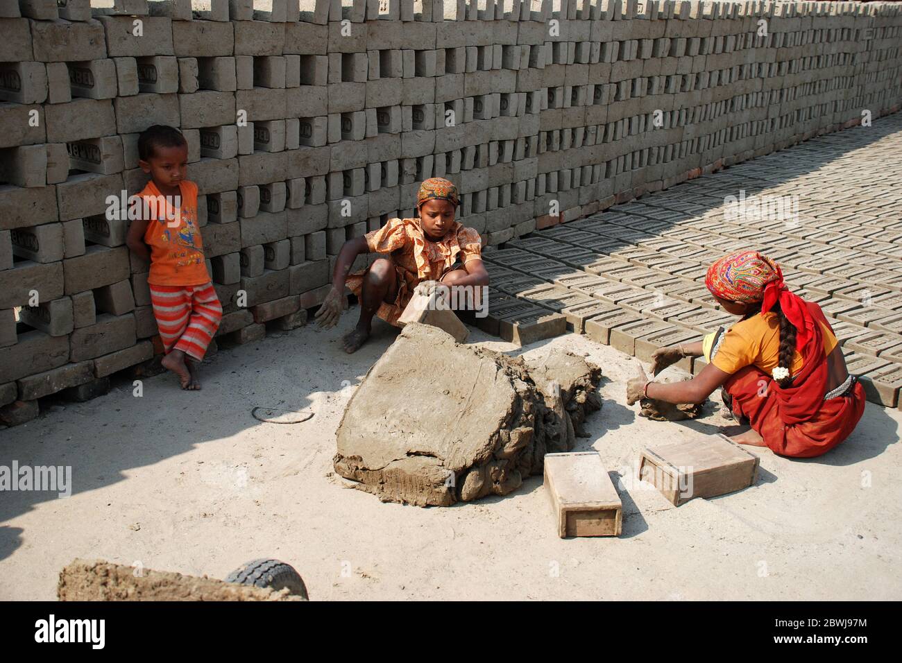 Labourers prepare bricks at a brick kiln in Sarberia, West Bengal, India. The Indian brick industry is the second largest in the world after China. Stock Photo