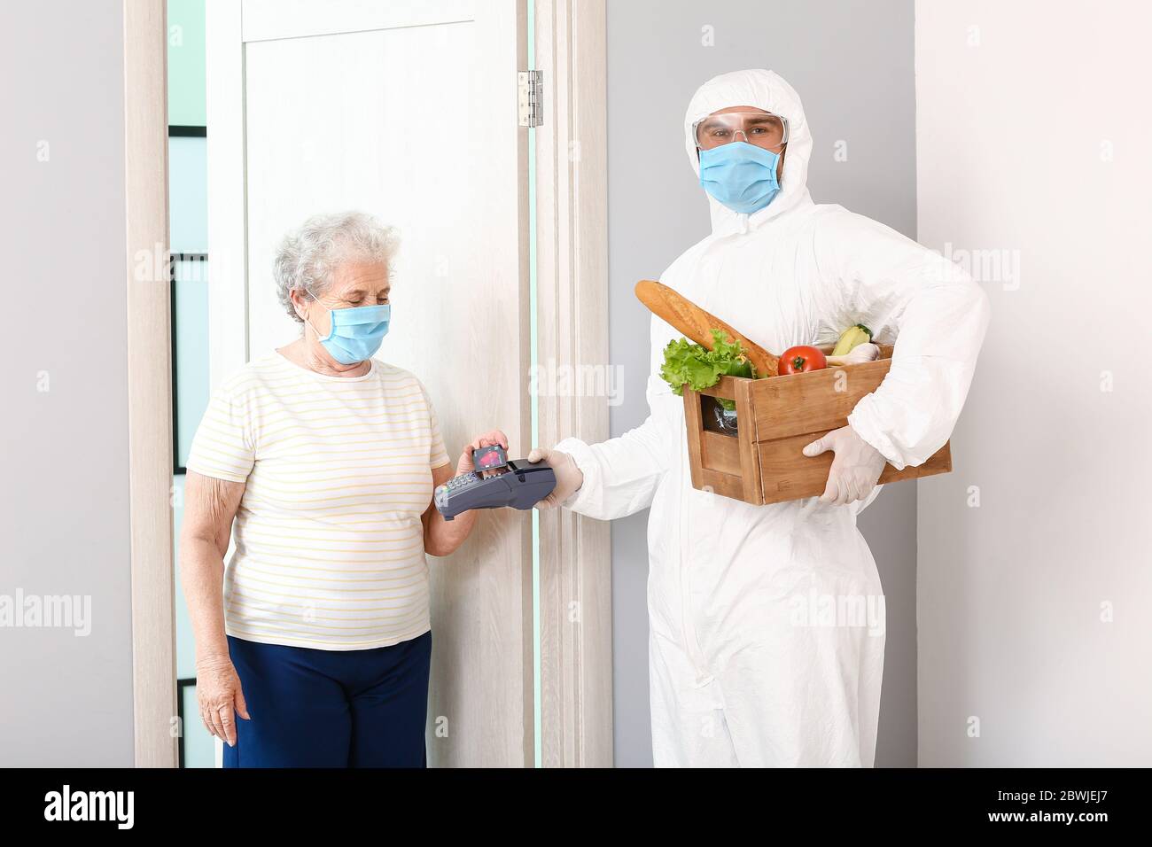 Elderly woman paying courier of food delivery company for order via