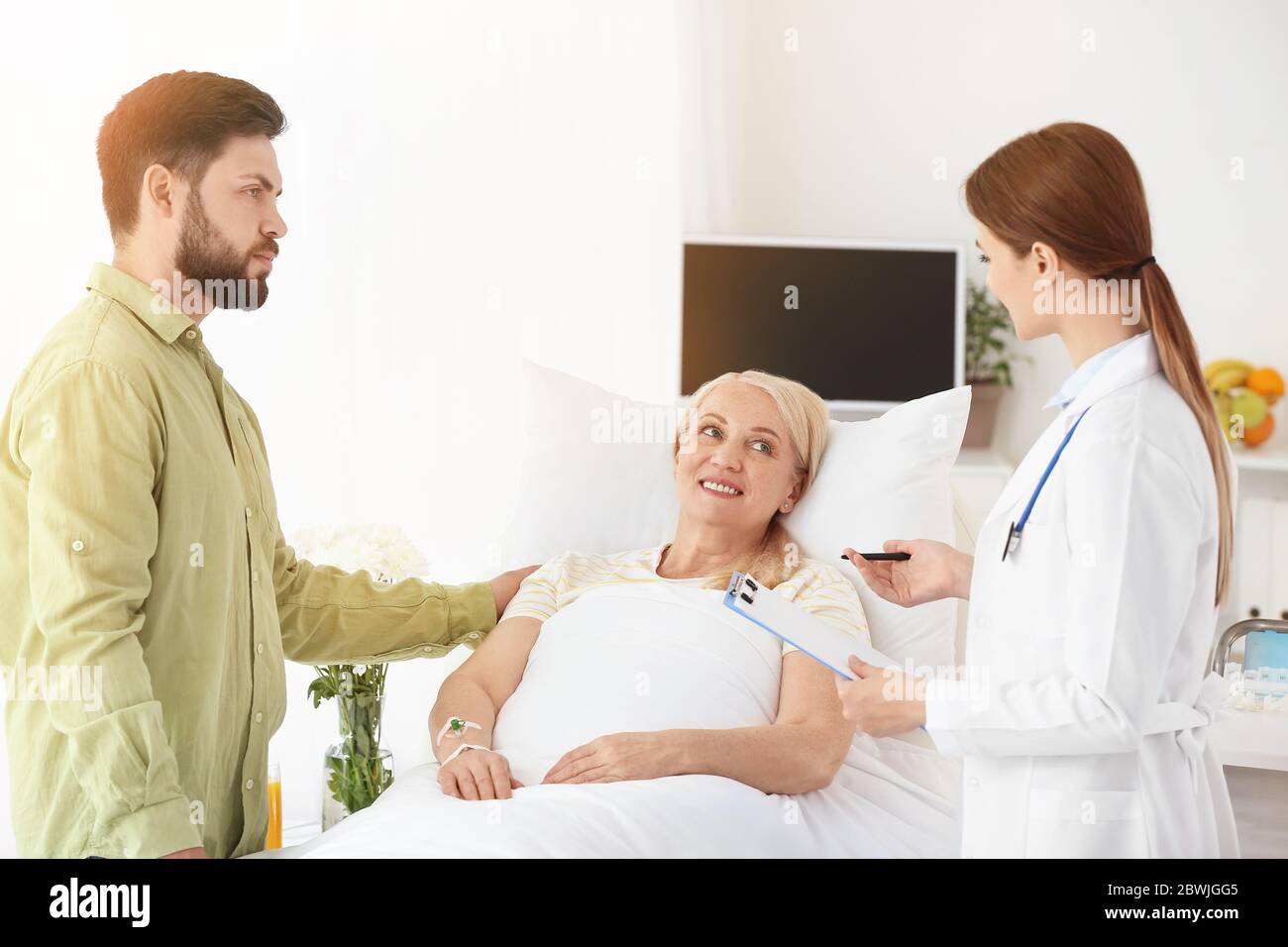 Mature woman with doctor and son in hospital room Stock Photo - Alamy