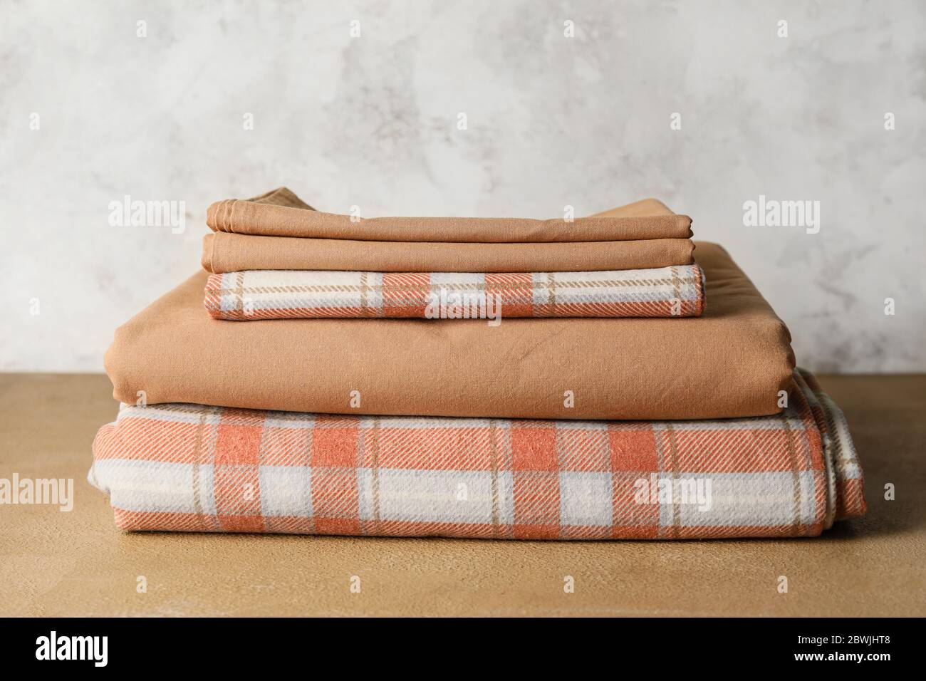 Stack of clean bed sheets on table Stock Photo