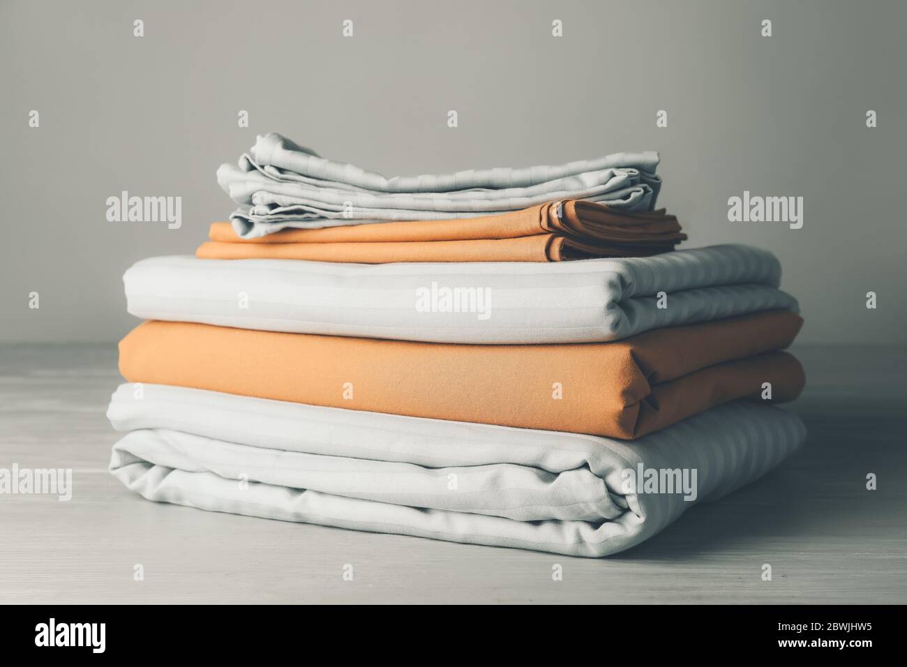 Stack of clean bed sheets on table Stock Photo