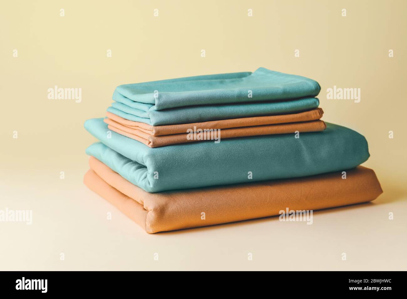 Stack of clean bed sheets on color background Stock Photo