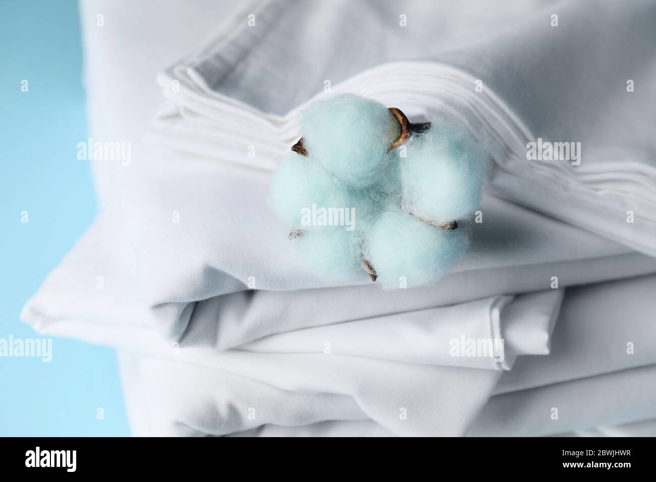 Stack of clean bed sheets on color background, closeup Stock Photo