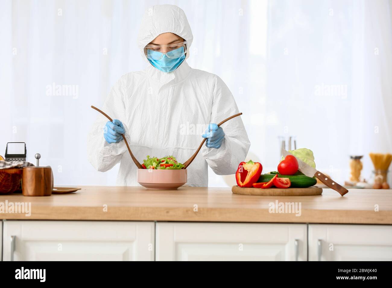 Woman in biohazard suit cooking in kitchen Stock Photo - Alamy