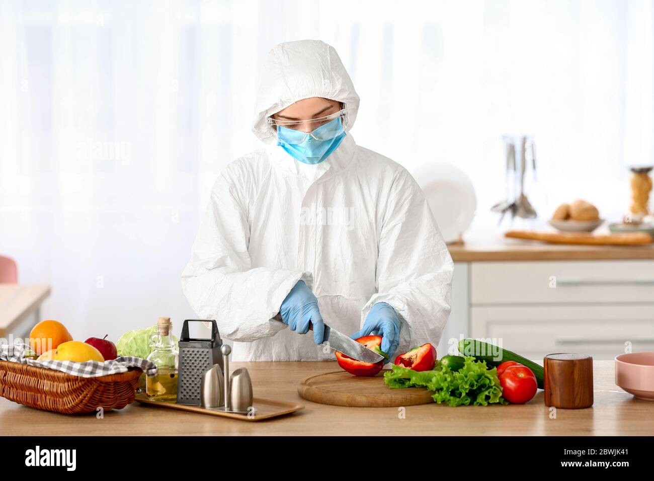 Woman in biohazard suit cooking in kitchen Stock Photo - Alamy