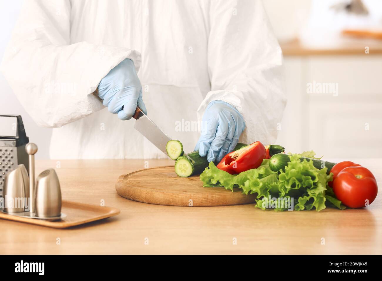 Woman in biohazard suit cooking in kitchen Stock Photo - Alamy